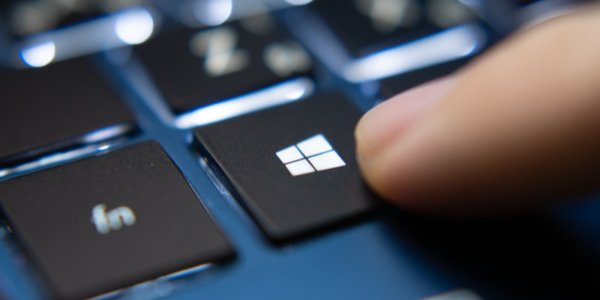 A finger pressing the windows key on a keyboard