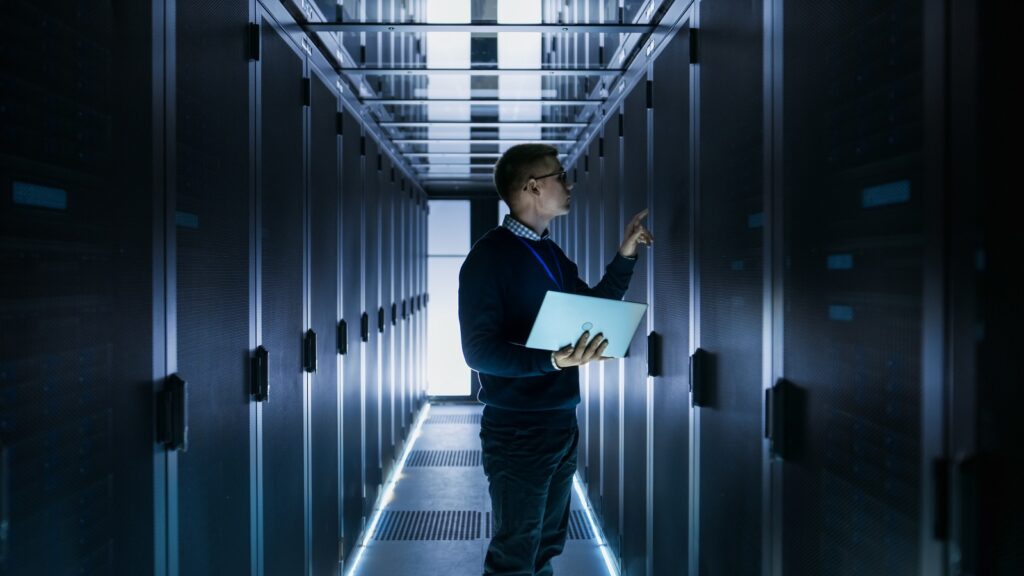 A man looking at servers in a dark room