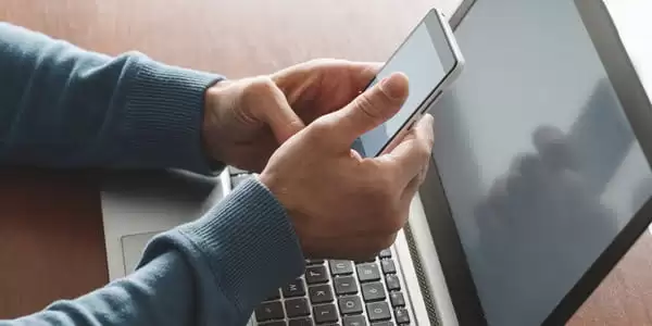 Person browsing phone infront of computer